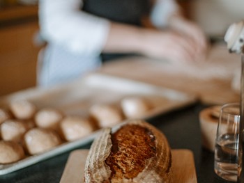 Tipps und Trick zu Brot und Handgebäck Brot auf einer Anrichte vor einem Blech mit Teiglingen