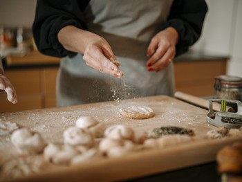 Kneten, formen und backen mit Bäckerin Christine Frau streut Mehl über einen Teigling