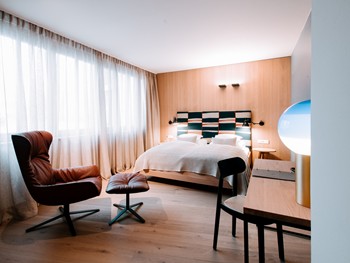 Ein gemütliches Doppelzimmer. Zum Wohnen gemacht. Hotelzimmer mit Doppelbett, Sitzecke und Fensterfront