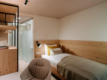 Cosy single room with French balcony Single bed, armchair and open wardrobe in the hotel room