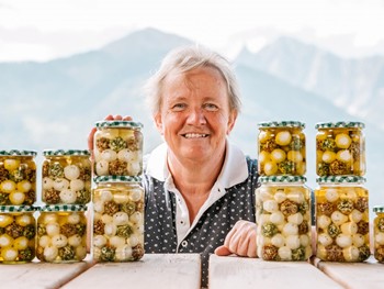 Frau, umgeben von Einmachgläsern, lächelt in die Kamera