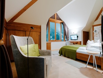 The loft offers plenty of space and high ceilings Armchair and double bed in the hotel room