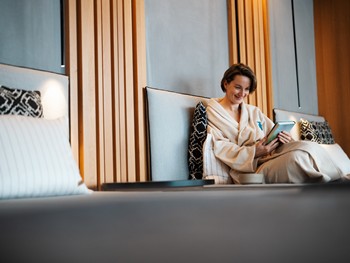 Frau im Bademantel auf einer Liegefläche liest ein Buch