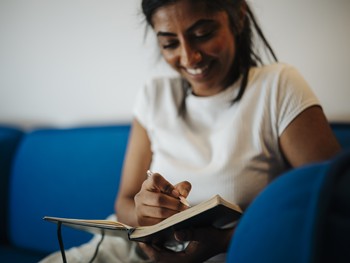 Woman writes in notebook and laughs