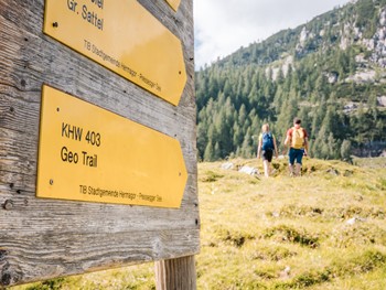 Sign with hiking trails, two hikers in the background