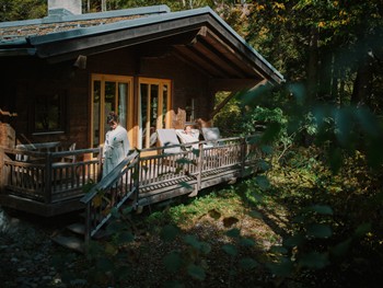Enjoy wellness on the quiet edge of the forest Couple in bathrobes in front of a wooden hut in the forest