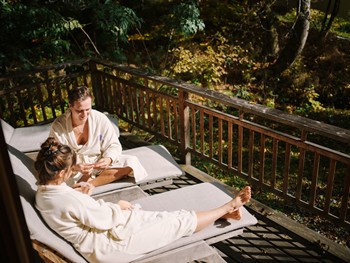 Two people in bathrobes lying on a terrace