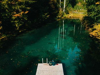 Couple sitting on a footbridge in a pond in the forest