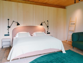 Genießen Sie Ihr helles Zimmer mit mutigen Farbklecksen Hotelzimmer mit rosa Bett und dunkelgrüner Couch
