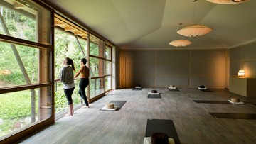 Zwei Frauen in einem Yogaraum am offenen Fenster schauen nach Draußen