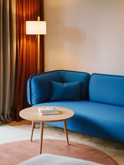 Blue couch in the hotel room with side table and lamp
