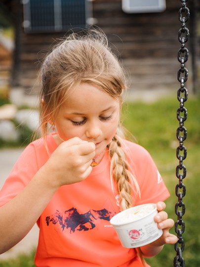 Girl eating ice cream from a cup in the garden