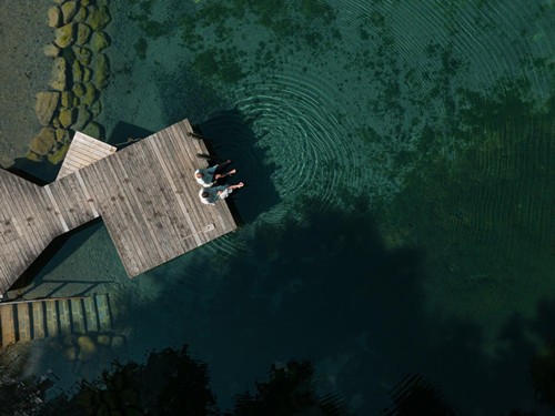 Person on a jetty surrounded by water from above