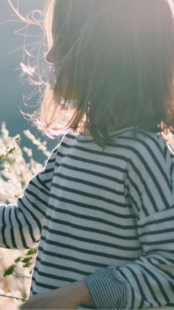Child stands in the field and touches a grain stalk
