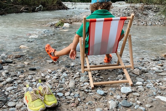 Child sitting in a deckchair on the riverbank