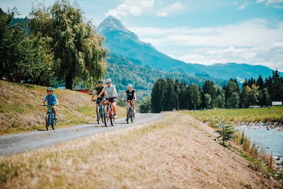 Family on bicycles riding along the river