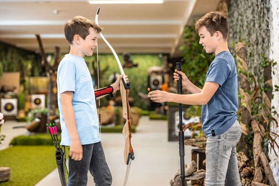 Two boys with bows and arrows in a hall
