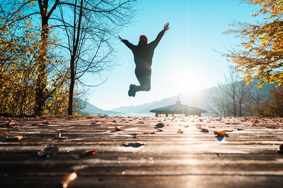Person in autumn landscape jumps into the air