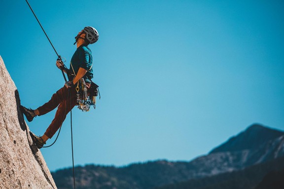Climber on a rock face holding a rope in his hand