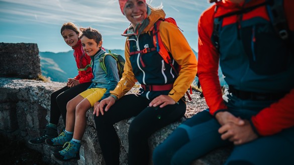 Family in hiking clothes sitting on a stone wall