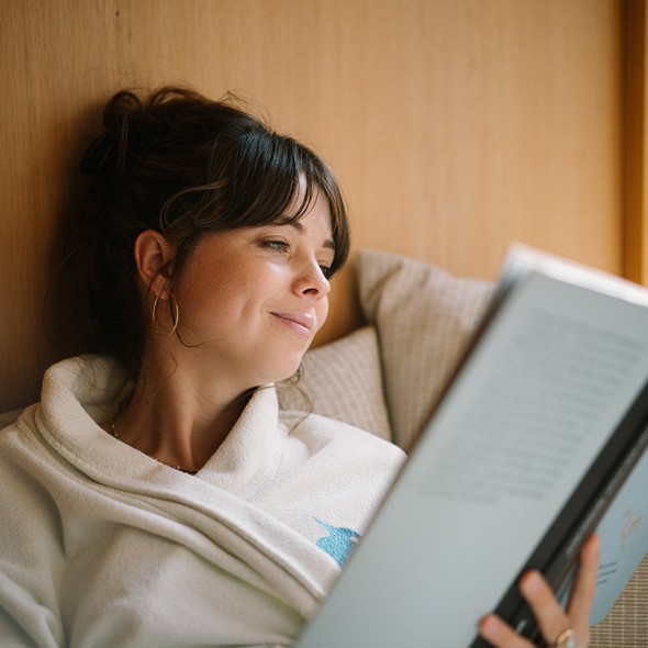 Frau im Bademantel liest ein Buch